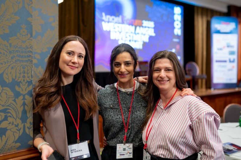Ania Wysocka posing with two other attendees at the Western Angel Investment Summit 2025, all wearing conference lanyards